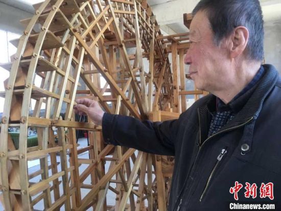图为78岁的段怡村介绍黄河水车结构原理。　张婧摄