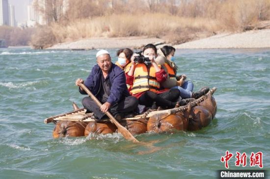 2月24日，年�^七旬的�m州羊皮筏子制作技�第三代�鞒腥��德��在�S河上��著羊皮筏子。(�Y料�D) 九美旦增 �z