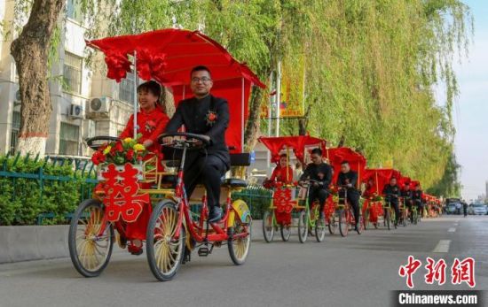 甘肃庆阳市举行以“五四精神革故鼎新 移风易俗青年先行”为主题的集体婚礼。图为新人骑车迎亲。(资料图) 陈飞 摄