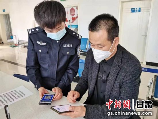 图为灵台县公安局出入境窗口民警指导群众下载安装国家反诈中心APP